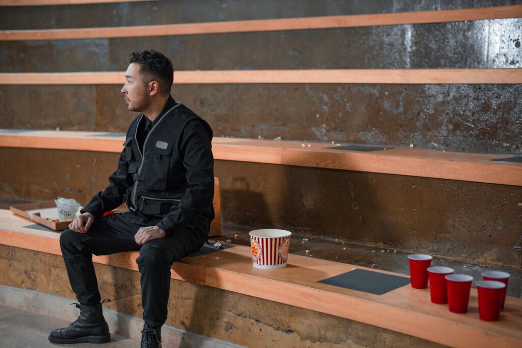 A Man in Black Jacket Sitting on the Bleachers